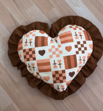 Heart-shaped pillow with checkered pattern and brown ruffle.