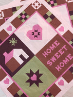 Quilt with geometric patterns and 'Home Sweet Home' text on a white background